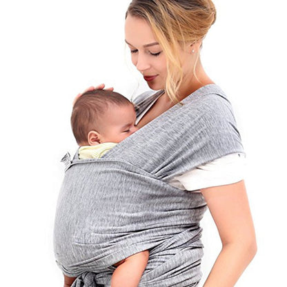 A baby sling wrap carrier with a sleeping infant inside, worn by an adult with one hand supporting the baby's head.