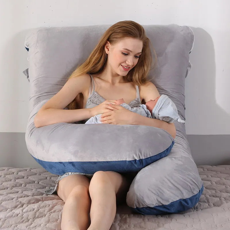 A pregnant woman lying on a gray pregnancy bump support pillow with a solid pattern.