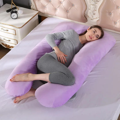 A pregnant woman lying on a purple pregnancy bump support pillow with a solid pattern.