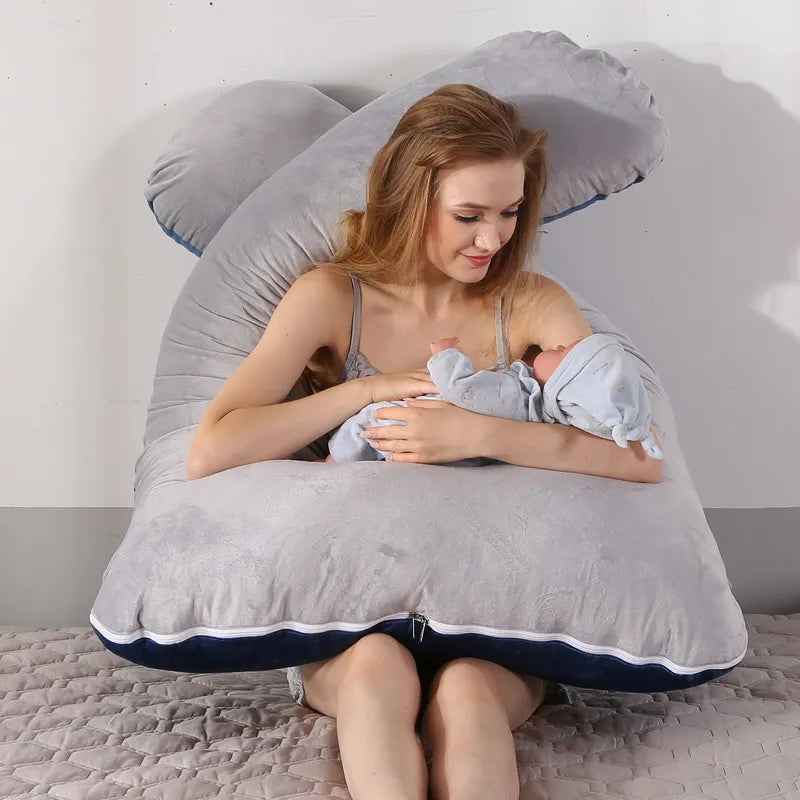 A pregnant woman lying on a light gray pregnancy bump support pillow with a solid pattern.