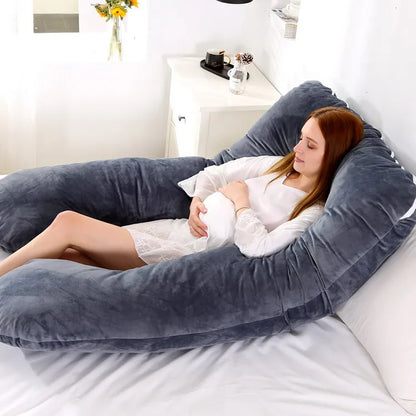 A pregnant woman lying on a blue pregnancy bump support pillow with a solid pattern.