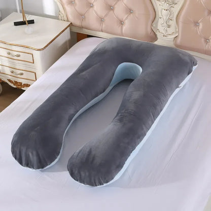 A pregnant woman lying on a gray / blue pregnancy bump support pillow with a solid pattern.