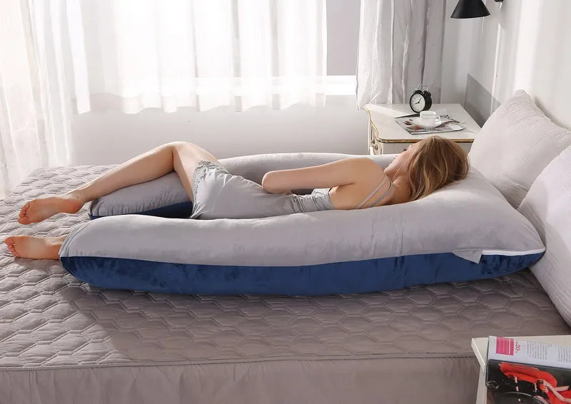 A pregnant woman lying on a gray pregnancy bump support pillow with a solid pattern.