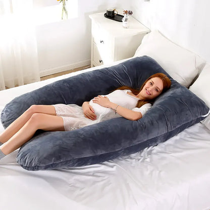 A pregnant woman lying on a blue pregnancy bump support pillow with a solid pattern.