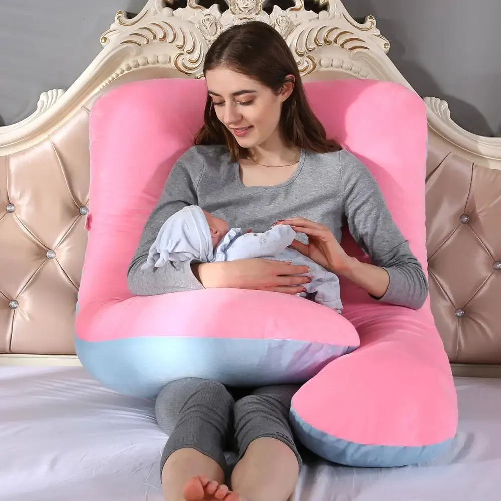 A pregnant woman lying on a pink pregnancy bump support pillow with a solid pattern.