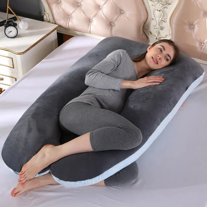 A pregnant woman lying on a gray pregnancy bump support pillow with a solid pattern.