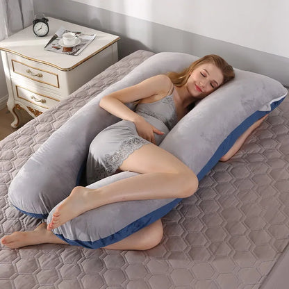 A pregnant woman lying on a gray pregnancy bump support pillow with a solid pattern.