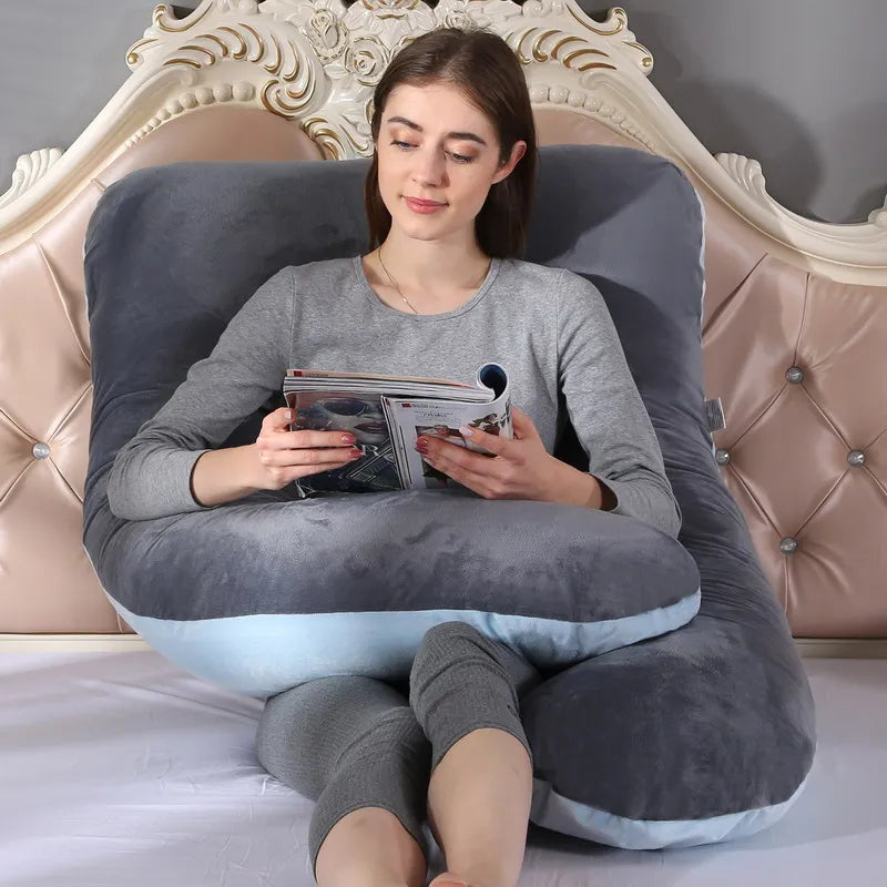 A pregnant woman lying on a gray pregnancy bump support pillow with a solid pattern.