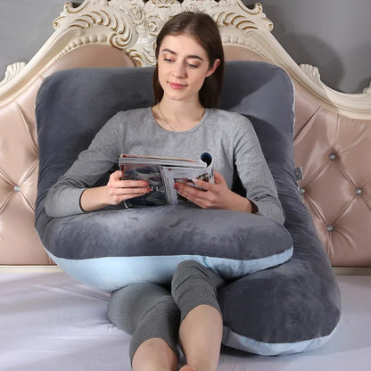 A pregnant woman lying on a gray pregnancy bump support pillow with a solid pattern.