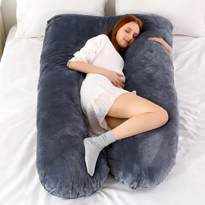 A pregnant woman lying on a gray pregnancy bump support pillow with a solid pattern.